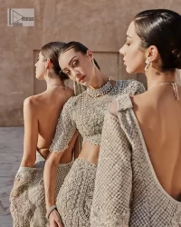 This fusion of floral embroidery is total fashion goodness for a walima outfit! A stunning teal grey organza choli embellished with intricate detailing finished with a scalloped border. The beautiful blouse is decorated with silver embellishment which is further prominent with tilla,daka, kora, Kundan and the real magic of Zardozi.  It is paired with a heavily embellished back-train lehenga with botanical motifs and geometric patterns. Its dupatta is made from a net. The dupatta is a wide embellished border that added divine charm to the entire ensemble.