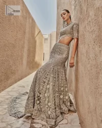 This fusion of floral embroidery is total fashion goodness for a walima outfit! A stunning teal grey organza choli embellished with intricate detailing finished with a scalloped border. The beautiful blouse is decorated with silver embellishment which is further prominent with tilla,daka, kora, Kundan and the real magic of Zardozi.  It is paired with a heavily embellished back-train lehenga with botanical motifs and geometric patterns. Its dupatta is made from a net. The dupatta is a wide embellished border that added divine charm to the entire ensemble.