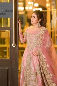 DeemasFashion presents this wedding outfit which is an embellished masterpiece that wins everyone’s hearts at the very first glance with its charm and elegance. The Maxi in the Pink colour has laden with Golden embroidery which makes this attire a head-turning masterpiece. Further, the round neckline is fully embellished with tilla, dabka, kora, Kundan, and pearls that is giving it a magical look. The fullsleeves style makes this outfit a little attractive but super charming. Complete this article with a dupatta, framed with a four-sided border.