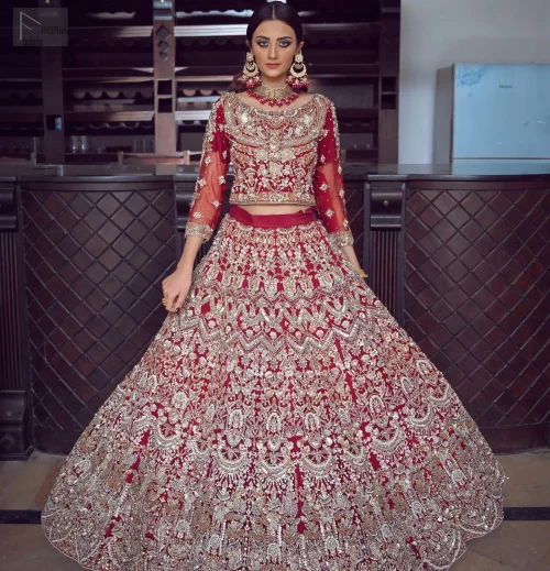 This luxurious lehenga cascades in a dramatic fit-and-flare silhouette in a deep maroon hue, perfect for making a grand entrance.