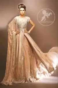 Pale peach side open double layer bridal wear maxi dress with heavy embroidered bodice and border on side slit. Large motifs implemented on inner layer.